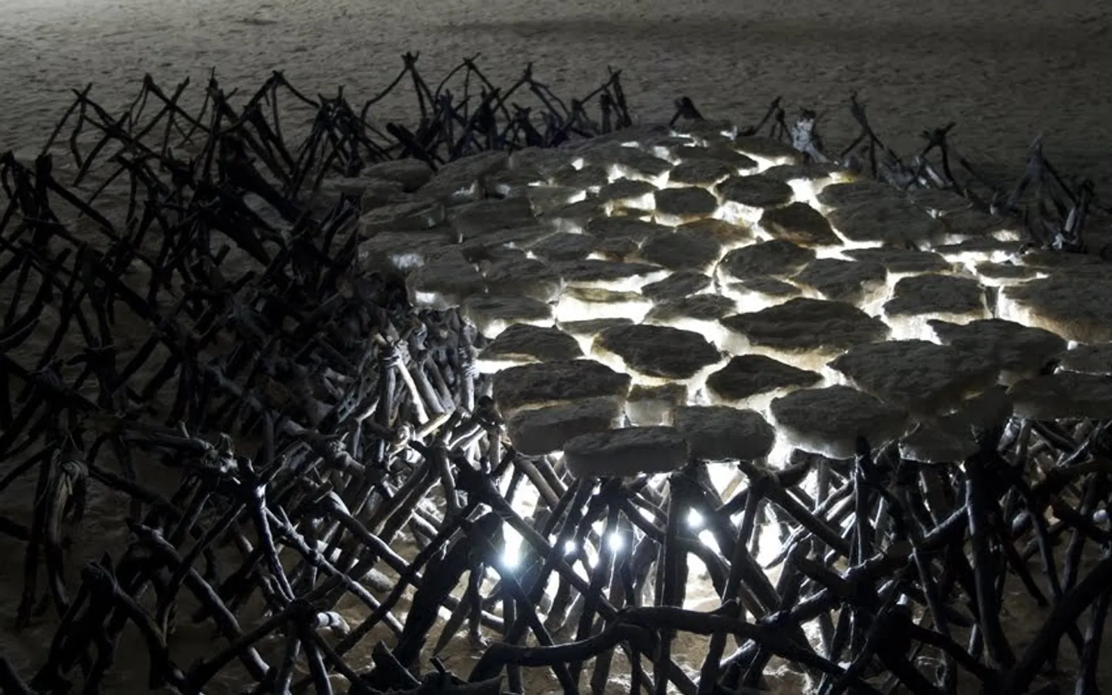 The Servants' Bed, 2009 — salt blocks lit from within, resting on a tangle of charred wood